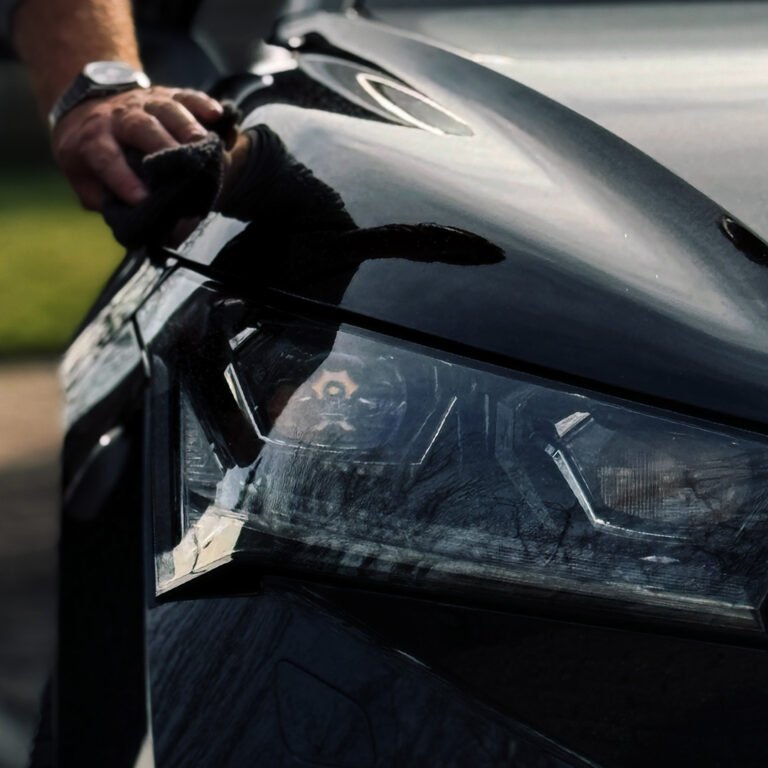 poetsdoek langs zwarte auto een hand met horloge heeft de poetsdoek vast