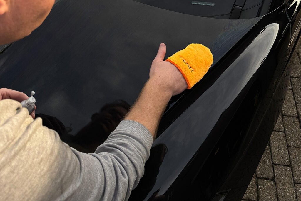 foto van hand met applicator sleeve die de auto zelf aan het coaten is