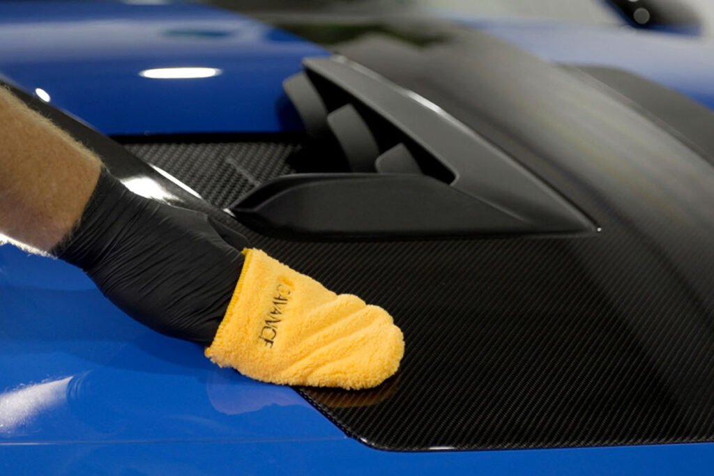 een hand die cavance coating aanbrengt op een porche motorkap