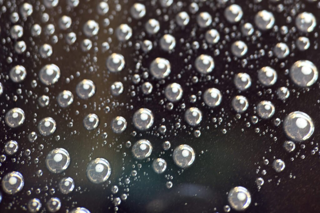 waterdruppels die parelen op zwarte lak